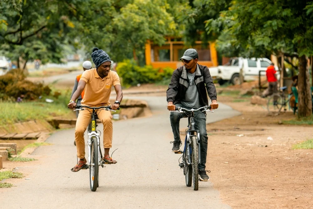 Two men cycling along a tree-lined road near Karatu