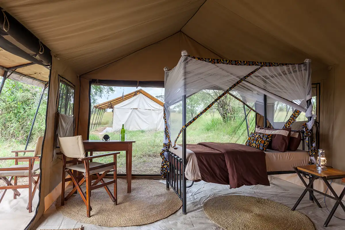 Gnu Mara River Camp guest tent with a canopy bed and veranda