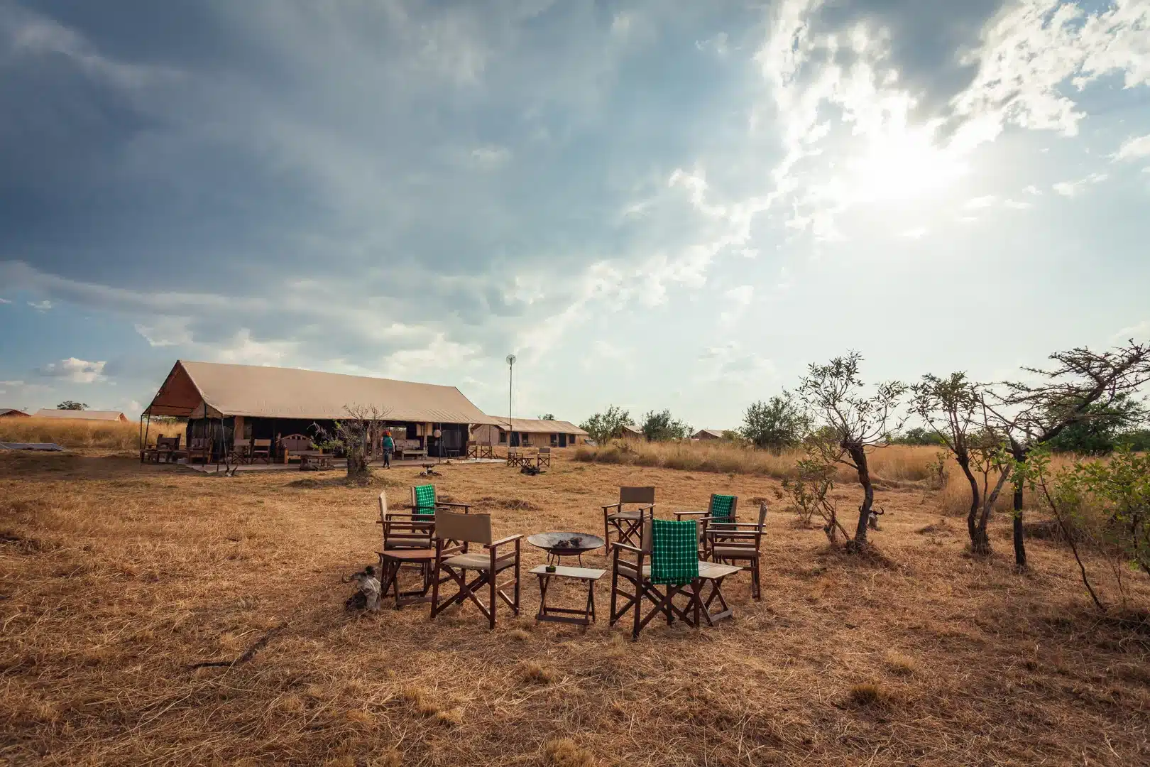 Campfire chairs on the dry grass in front of the main tent at Gnu Mara River Camp