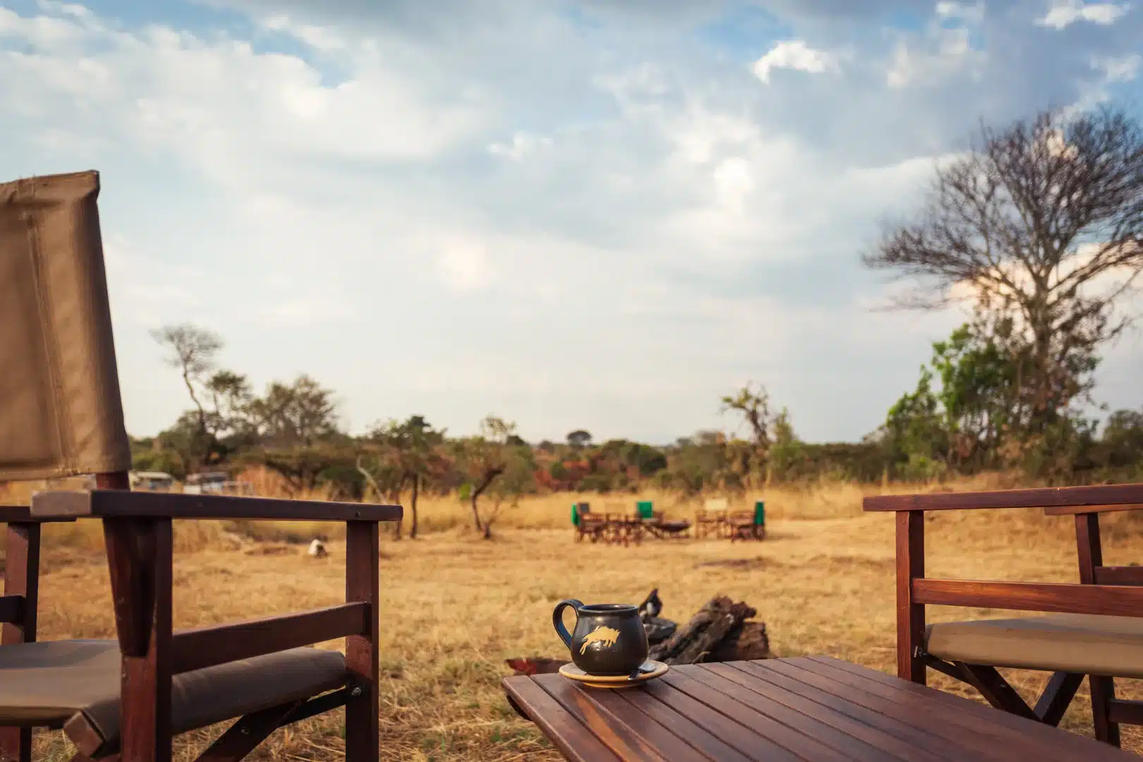 A mug of coffee on the table, looking out towards the campfire and the plains