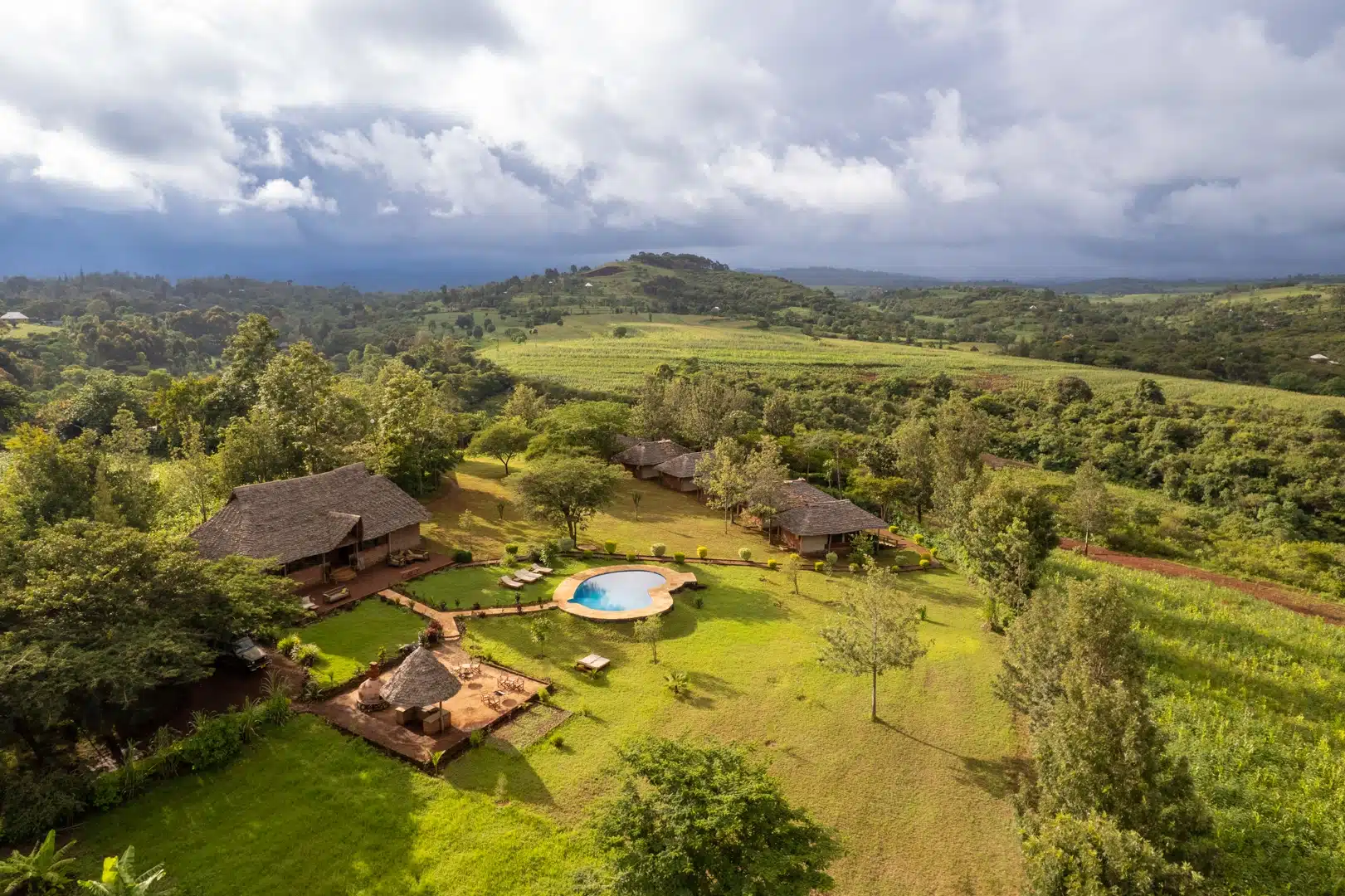 Aerial view of Karatu Tented Lodge, its pool and the green hills around it