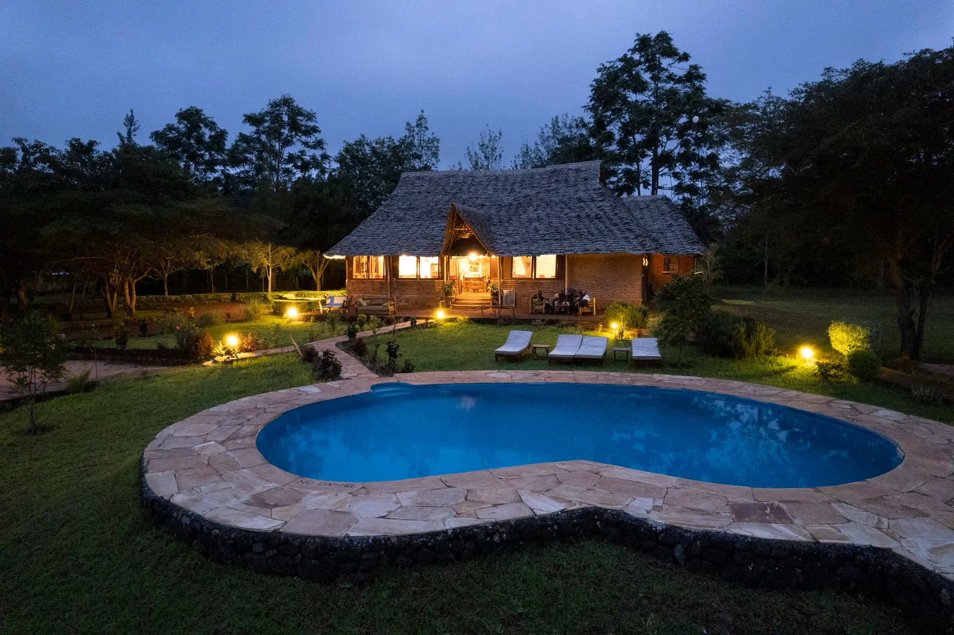 Mawe Lodges at night features a small camp with a pool, highlighting its charm within Tanzania Safari Lodges and Camps.