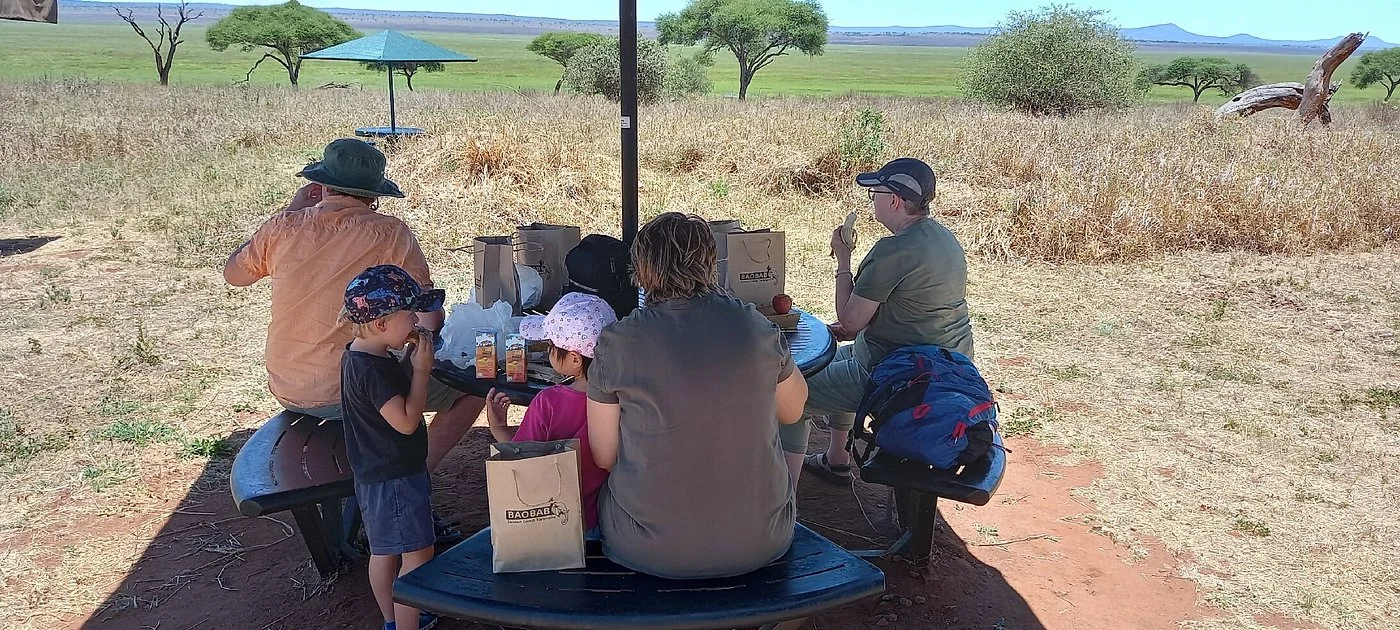 A family having a picnic lunch at a table on the plains