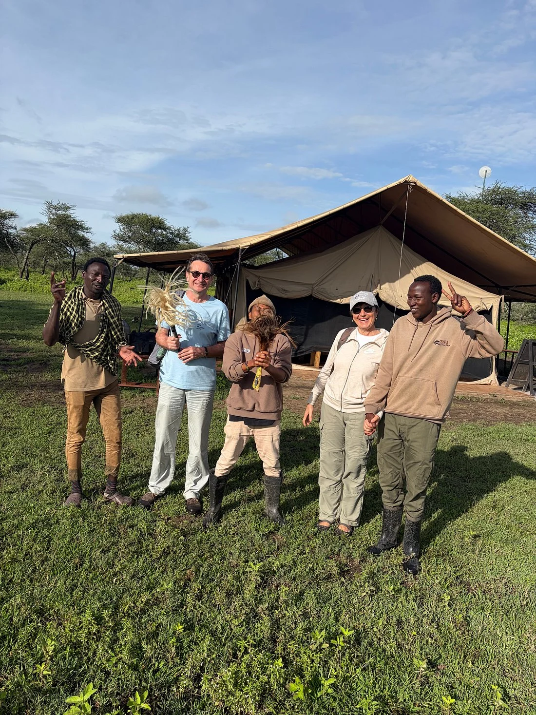 Guests and camp crew standing together outside a safari tent