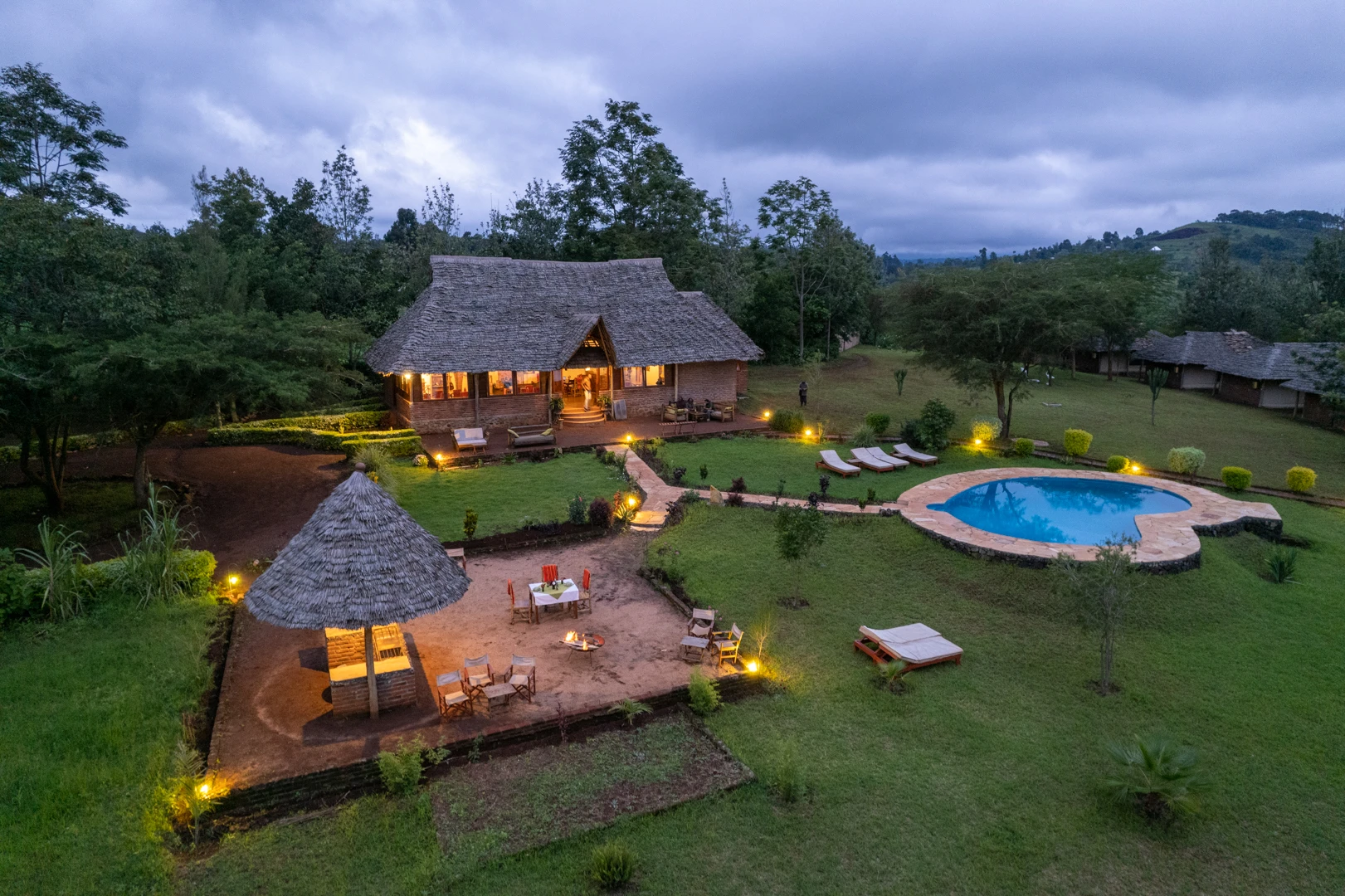 Aerial view of the lodge and pool lit at dusk